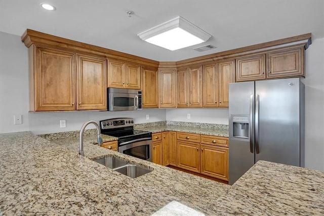 kitchen featuring kitchen peninsula, light stone countertops, sink, and appliances with stainless steel finishes