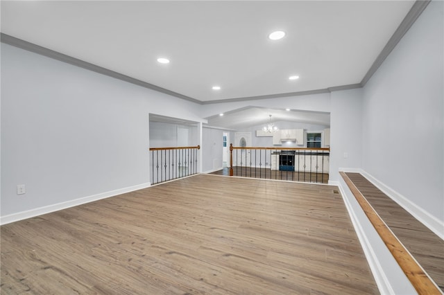 unfurnished room featuring crown molding, a chandelier, vaulted ceiling, and hardwood / wood-style flooring