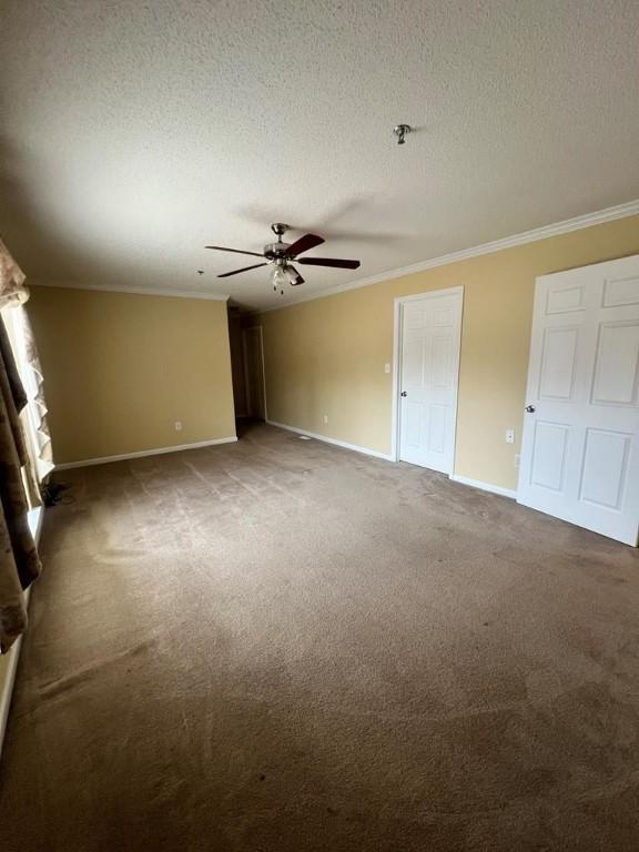 interior space with ceiling fan, dark colored carpet, a textured ceiling, and ornamental molding