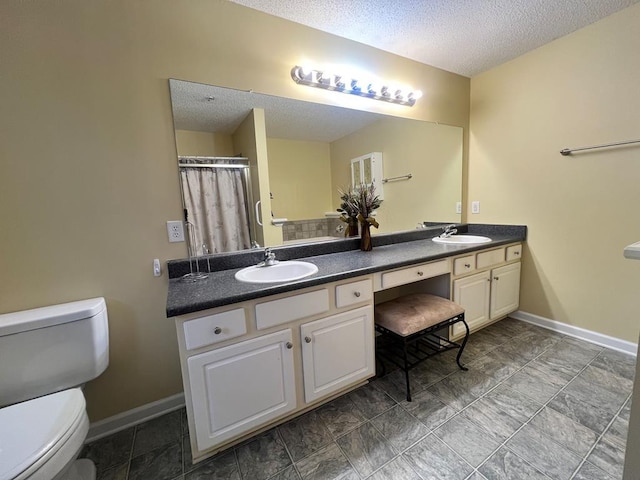 bathroom with vanity, curtained shower, toilet, and a textured ceiling