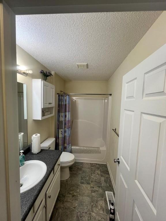 full bathroom featuring vanity, shower / bath combination with curtain, toilet, and a textured ceiling