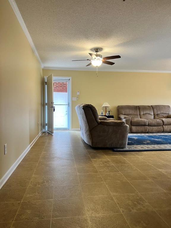 living room with ceiling fan, a textured ceiling, and ornamental molding