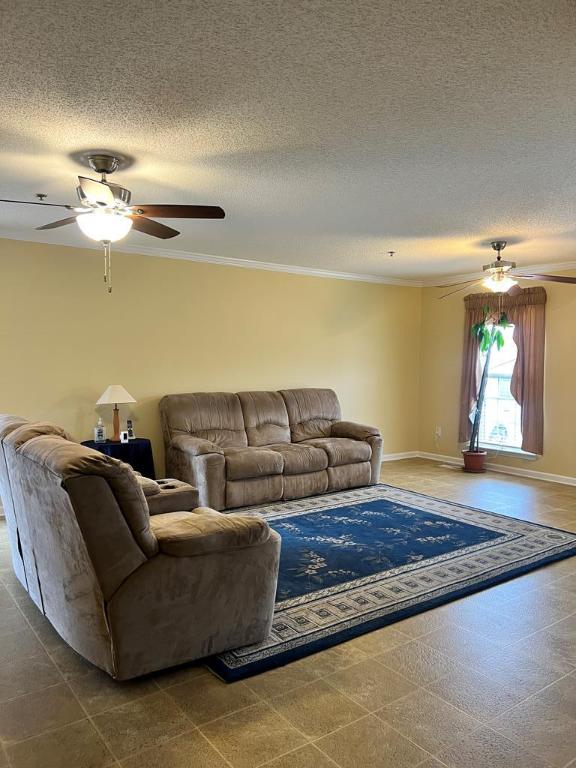 living room with ceiling fan, a textured ceiling, and ornamental molding