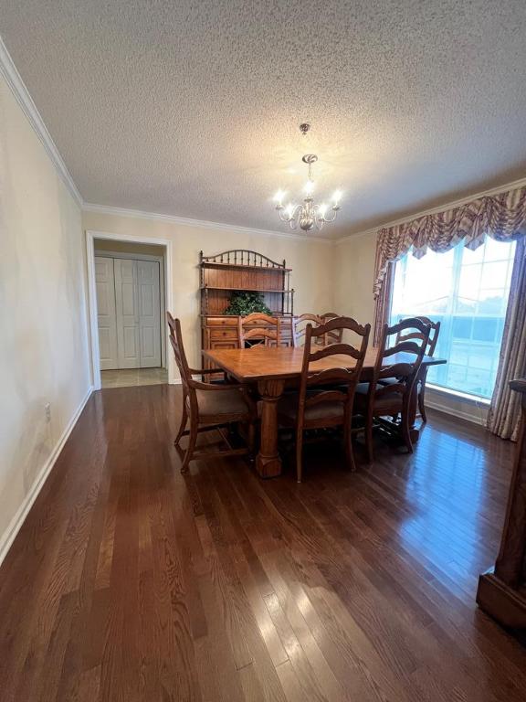 dining space featuring dark hardwood / wood-style flooring, a textured ceiling, crown molding, and a notable chandelier