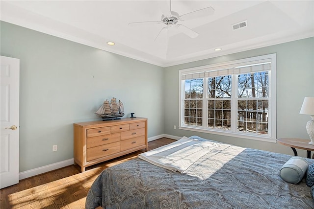 bedroom featuring hardwood / wood-style floors, a tray ceiling, and ceiling fan