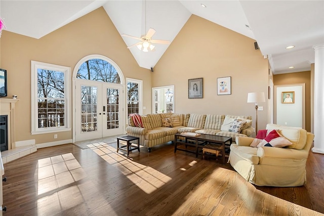 living room with hardwood / wood-style floors, a tiled fireplace, high vaulted ceiling, and french doors