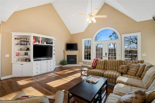 living room featuring ceiling fan, french doors, high vaulted ceiling, dark hardwood / wood-style floors, and a tiled fireplace