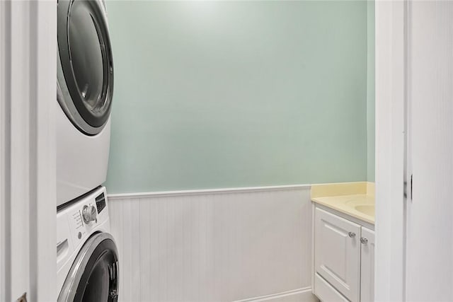 laundry room featuring stacked washer / dryer and cabinets