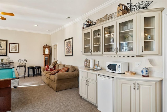 bar featuring sink, light colored carpet, white appliances, white cabinets, and ornamental molding