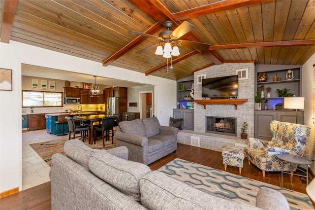 living room with sink, wooden ceiling, lofted ceiling with beams, a fireplace, and ceiling fan with notable chandelier