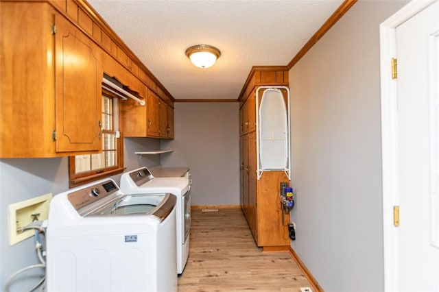 laundry room featuring washer and clothes dryer, cabinets, crown molding, light hardwood / wood-style flooring, and a textured ceiling