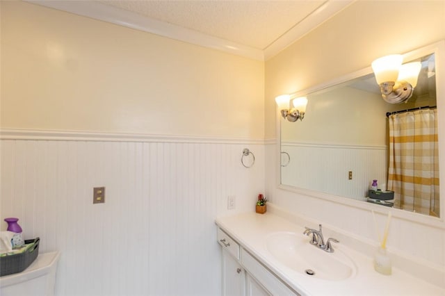 bathroom with a textured ceiling, vanity, toilet, and crown molding