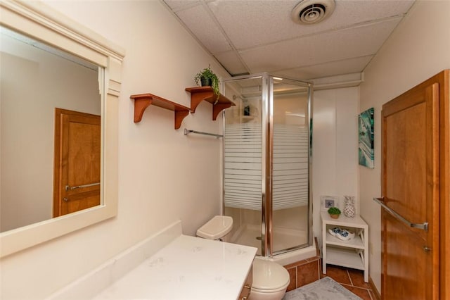 bathroom featuring a drop ceiling, tile patterned flooring, toilet, a shower with door, and vanity