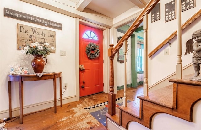foyer entrance featuring stairway, beam ceiling, wood finished floors, and baseboards