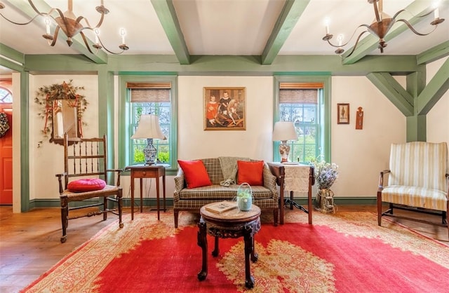 living area featuring beam ceiling, wood finished floors, a notable chandelier, and baseboards