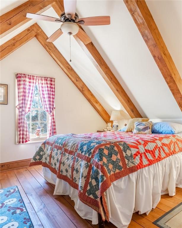 bedroom with light wood-style flooring, ceiling fan, and vaulted ceiling with beams