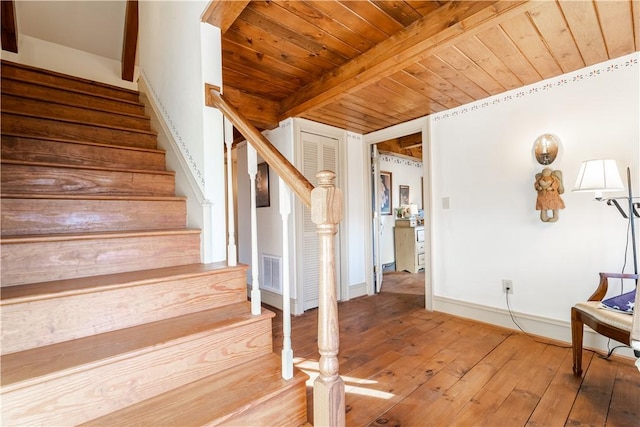 stairs featuring wooden ceiling, hardwood / wood-style floors, beamed ceiling, baseboards, and visible vents