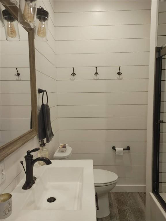 bathroom featuring wooden walls, toilet, vanity, and hardwood / wood-style flooring