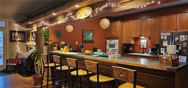 kitchen with pendant lighting, crown molding, white double oven, and sink