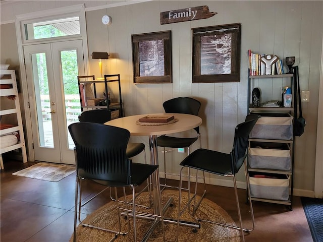 dining room featuring wood walls, french doors, and ornamental molding