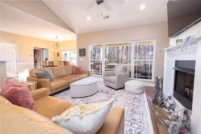 living room with hardwood / wood-style flooring, plenty of natural light, lofted ceiling, and ceiling fan with notable chandelier