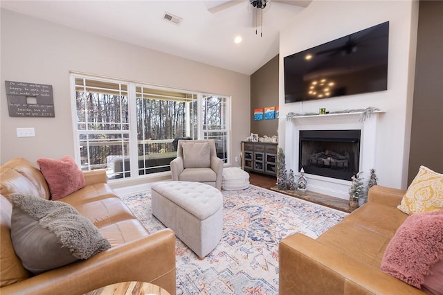 living room with ceiling fan, hardwood / wood-style floors, and vaulted ceiling