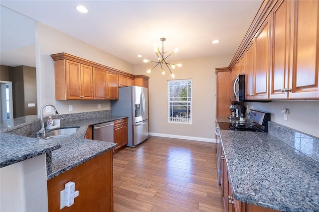 kitchen featuring kitchen peninsula, appliances with stainless steel finishes, sink, decorative light fixtures, and an inviting chandelier