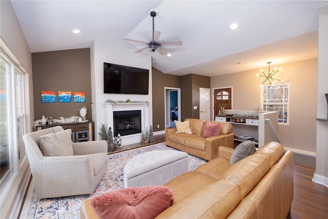 living room with lofted ceiling, hardwood / wood-style floors, and ceiling fan with notable chandelier