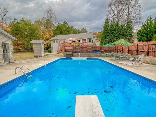 view of pool featuring a patio area, a diving board, and a storage shed