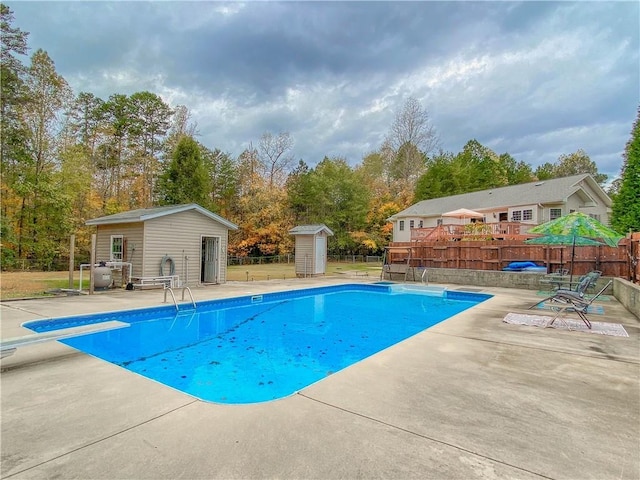 view of swimming pool with a patio, a shed, and a diving board