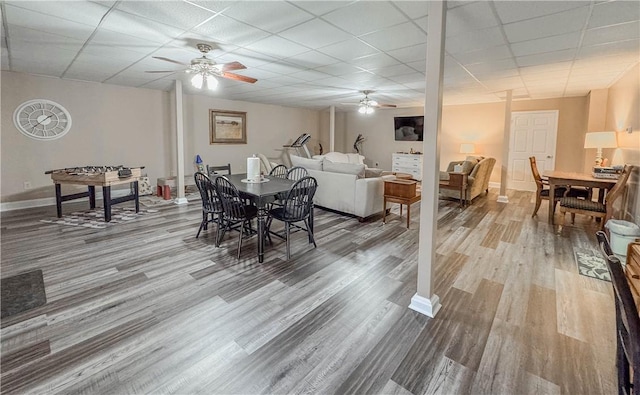 dining space featuring ceiling fan, a drop ceiling, and wood-type flooring