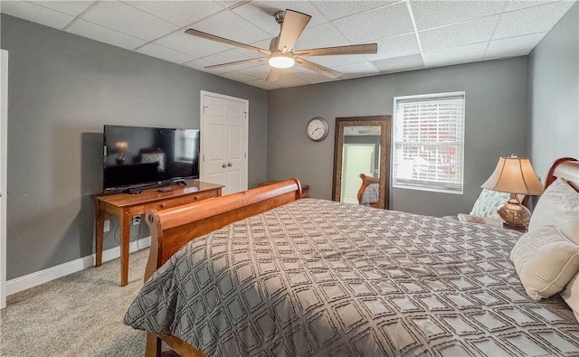 bedroom featuring ceiling fan, a drop ceiling, and light colored carpet