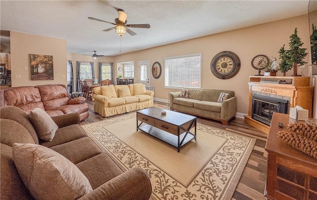 living room with ceiling fan, a fireplace, hardwood / wood-style floors, and a textured ceiling