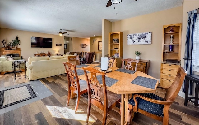 dining area with a textured ceiling, ceiling fan, and dark wood-type flooring