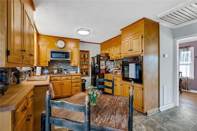 kitchen with sink, decorative backsplash, black appliances, and a textured ceiling