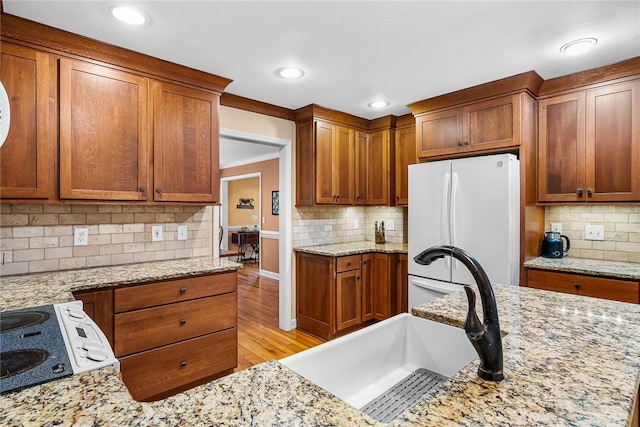 kitchen featuring white refrigerator, sink, light hardwood / wood-style flooring, light stone countertops, and ornamental molding