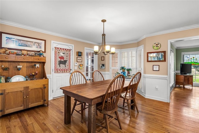 dining space featuring hardwood / wood-style flooring, crown molding, and an inviting chandelier