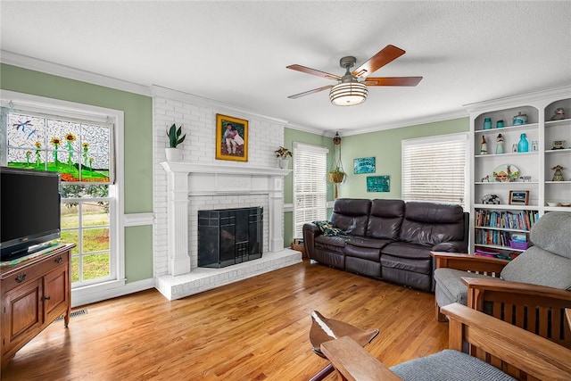 living room featuring plenty of natural light, light wood-type flooring, and ornamental molding