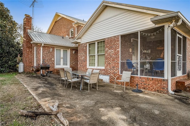 back of property with a sunroom, a patio, and french doors