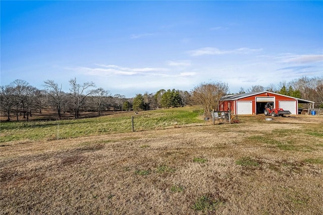 view of yard featuring an outbuilding, a rural view, and a garage