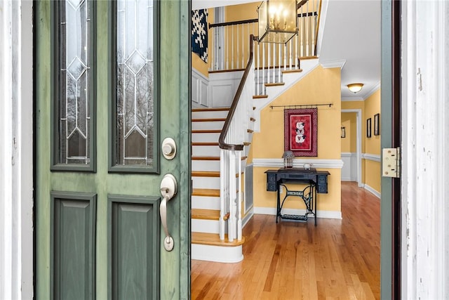 foyer entrance featuring wood-type flooring, a notable chandelier, and ornamental molding