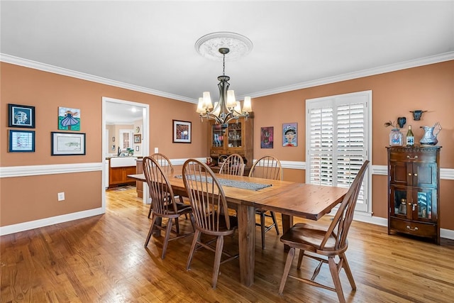 dining area featuring an inviting chandelier, crown molding, and light hardwood / wood-style flooring