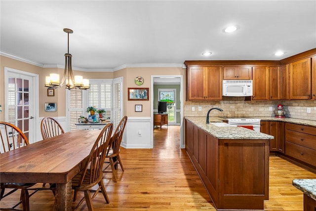 kitchen featuring white appliances, an inviting chandelier, hanging light fixtures, ornamental molding, and light stone counters