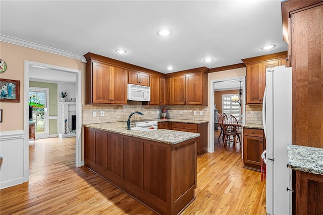 kitchen featuring crown molding, light stone counters, white appliances, and kitchen peninsula