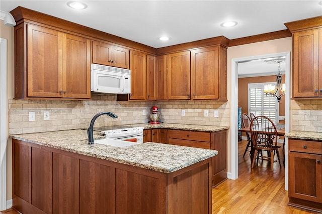 kitchen with white appliances, an inviting chandelier, crown molding, light stone countertops, and light wood-type flooring