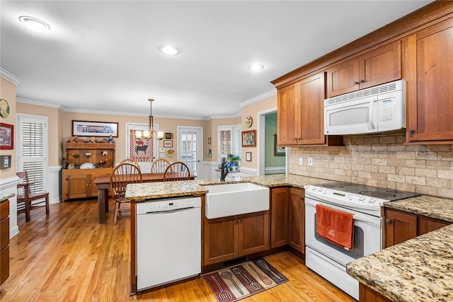 kitchen featuring kitchen peninsula, white appliances, sink, pendant lighting, and a notable chandelier