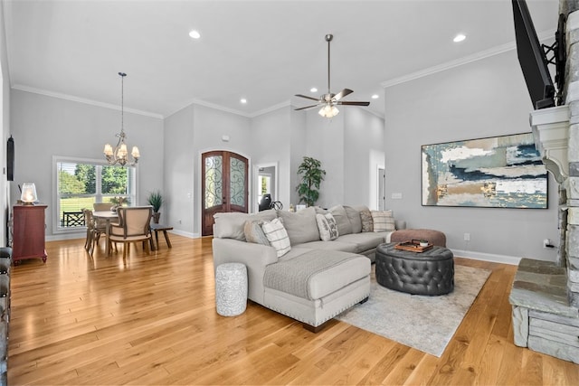 living room featuring crown molding, ceiling fan with notable chandelier, light hardwood / wood-style floors, and a high ceiling