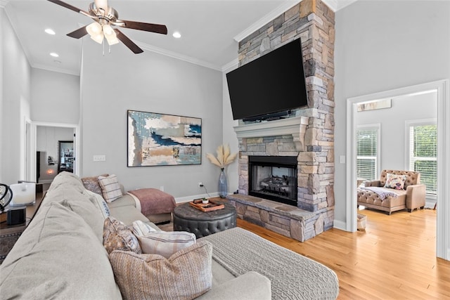 living room with crown molding, a fireplace, ceiling fan, and hardwood / wood-style floors