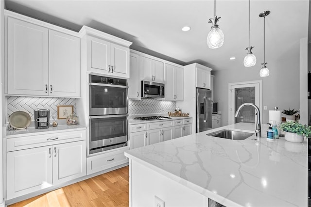 kitchen with white cabinets, appliances with stainless steel finishes, decorative light fixtures, and sink