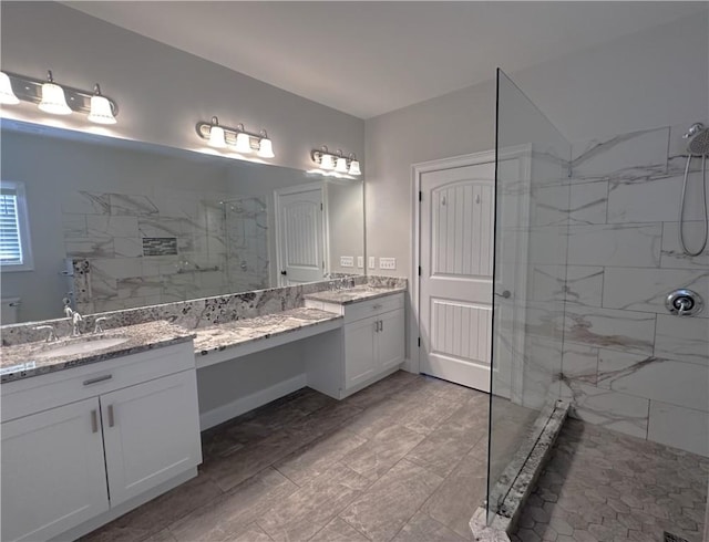 bathroom with a tile shower and vanity